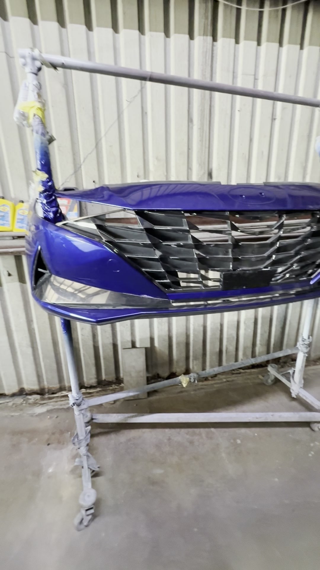 Freshly painted blue Hyundai Elantra bumper cover in INC Collision's paint area