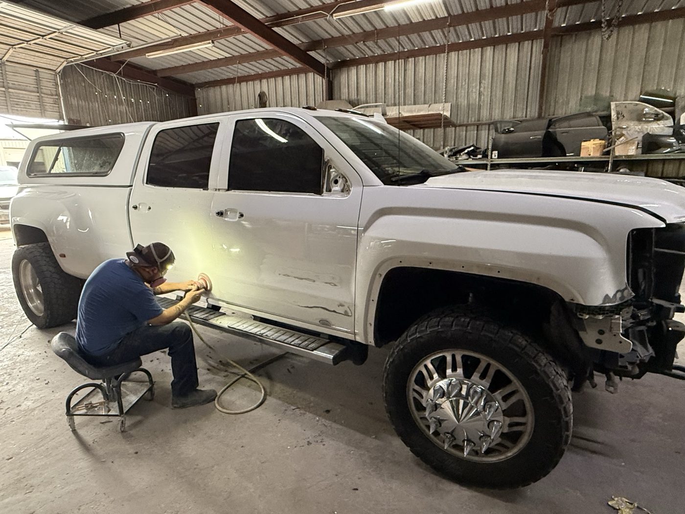 INC technician doing bodywork on a white GMC Denali dually inside the shop